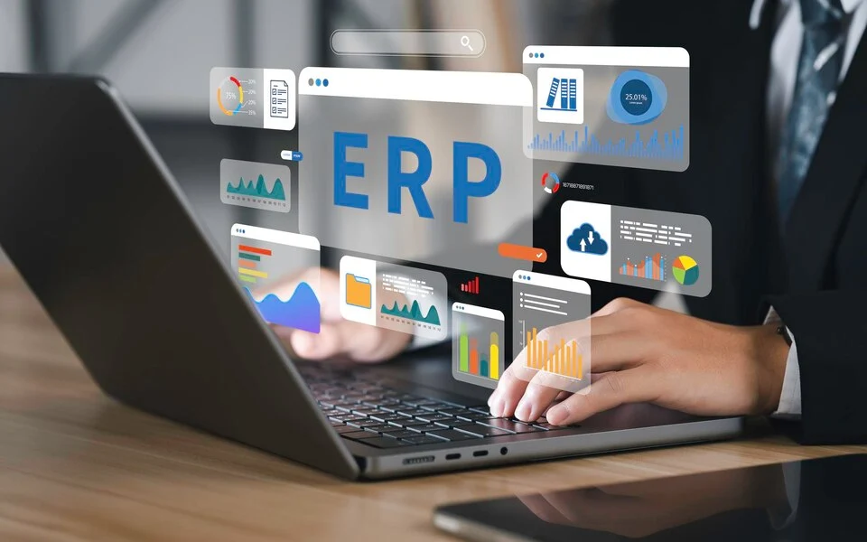 A corporate professional working on a laptop with some holographic bubbles popping out depicting the advancement of gNxtSuite ERP